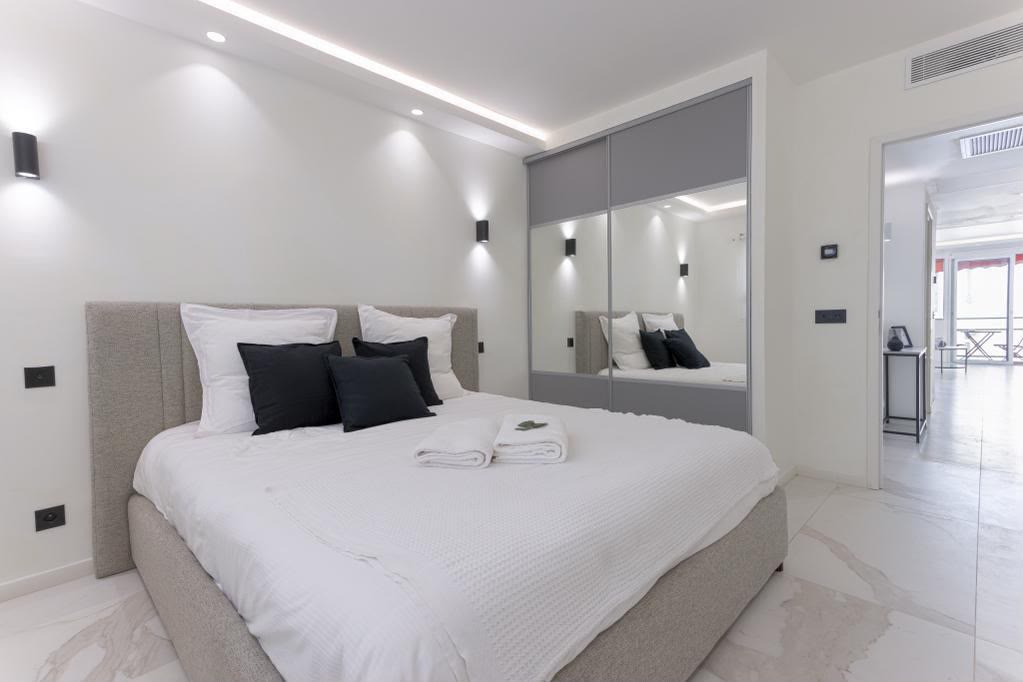 La chambre, sa tête de lit capitonnée et son grand dressing à portes miroir.