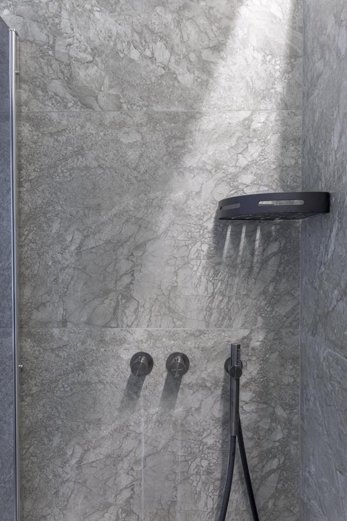 Douche à l'italienne habillée de marbre, robinetterie noire mate.